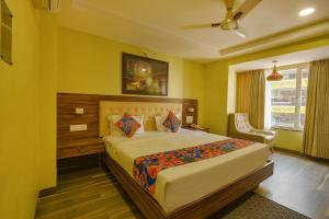 a bedroom with a bed and a chair and a window at FabHotel Phoenix Resorts in Bangalore