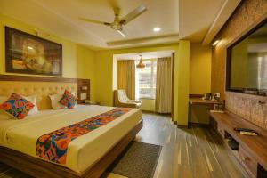 um quarto com uma cama e uma televisão de ecrã plano em FabHotel Phoenix Resorts em Bangalore