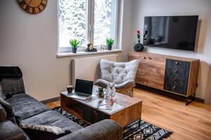 a living room with a couch and a laptop on a coffee table at Wójcik SPA - Krynica Zdrój in Krynica Zdrój