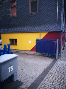 um edifício colorido com uma lata de lixo em frente em DK Glasmanufaktur GmbH em Wurzbach