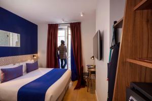 um quarto de hotel com uma cama e uma mulher a olhar pela janela em Paris Art Hotel Quartier Latin by Malone em Paris