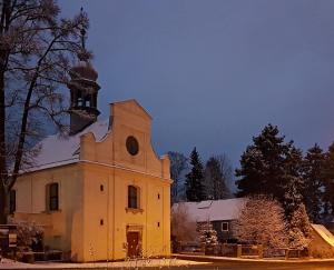 una vieja iglesia con una torre de reloj en la nieve en KostelApartmány en Liberec