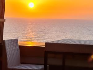 a table and a chair on a balcony with the sunset at Magic on the sea-suites with a private jacuzzi and a private sea view in Netanya