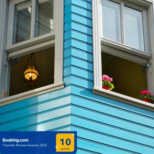 un edificio azul con dos ventanas con flores. en Tilas - Rooms in 19th Century Wooden Townhouse,Kadikoy en Estambul