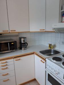 uma cozinha branca com um lavatório e um micro-ondas em Viihtyisä yksiö Oulun Tuirassa em Oulu