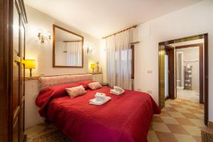 sypialnia z czerwonym łóżkiem i 2 ręcznikami w obiekcie Ca' Longhi w Wenecji