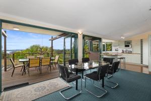 un soggiorno con tavolo e sedie e un balcone di Breezy on Broadview - Opua Holiday Home a Opua