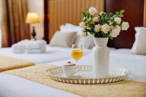 a table with a vase of flowers and a glass of wine at Garni Hotel Planeta Inn in Novi Sad