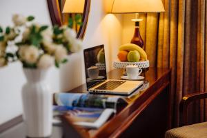 a desk with a laptop and a vase with fruit on it at Garni Hotel Planeta Inn in Novi Sad
