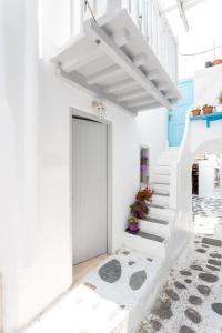 een witte hal met een witte trap en een deur bij aníko suites Chora in Mykonos-stad