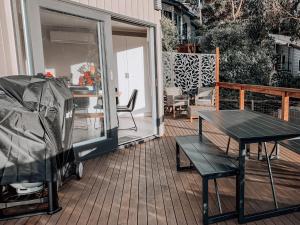 a patio with a table and a bench on a deck at Bay Views Lorne in Lorne
