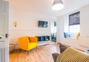 a living room with a yellow chair and a tv at Number 70 in Haddington