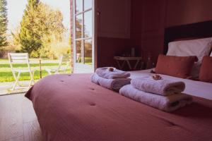 ein Schlafzimmer mit Handtüchern auf einem Bett mit einem großen Fenster in der Unterkunft Les jardins de Beaumont in 
