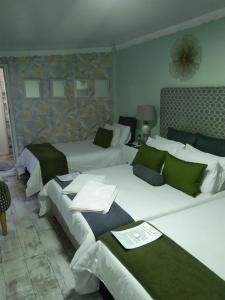 Habitación de hotel con 2 camas con almohadas verdes en Mitchell's Guesthouse, en Parow