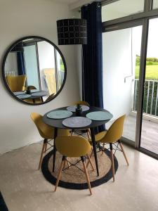 een eetkamer met een tafel, stoelen en een spiegel bij Résidence des 3 iles in Quiberon +4 foto's