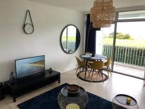 een woonkamer met een tv en een tafel en stoelen bij Résidence des 3 iles in Quiberon