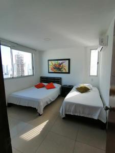 2 Betten in einem Zimmer mit weißen Wänden und Fenstern in der Unterkunft Apartamentos en Palmetto in Cartagena de Indias