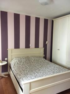ein Schlafzimmer mit einem Bett und einer gestreiften Wand in der Unterkunft Little Yellow House in Rijeka