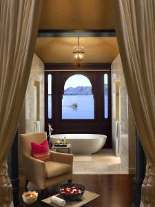 a bathroom with a tub and a chair and a window at The Leela Palace Udaipur in Udaipur