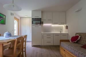 Una cocina y una sala de estar con una mesa y un sofá. en BAITA CUCOL: APPARTAMENTO CON GIARDINO PRIVATO, en Cogolo