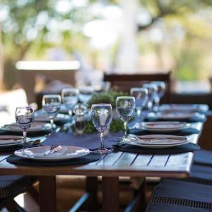 una mesa de madera con platos y copas de vino. en Buffalo Thorn Lodge, en Pilanesberg