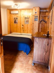 sypialnia z łóżkiem i drewnianą ścianą w obiekcie CASA VACANZE NORA w mieście Chamois