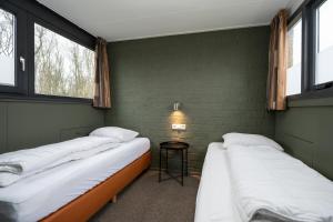 twee bedden in een kamer met twee ramen bij 't Eibernest in De Cocksdorp