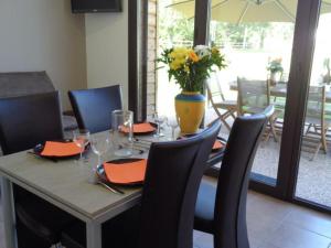 a dining table with chairs and a vase with flowers at Gîte Veauchette, 3 pièces, 4 personnes - FR-1-496-78 in Veauchette