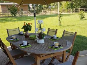 una mesa de madera con platos, tazas y flores. en Gîte Veauchette, 3 pièces, 4 personnes - FR-1-496-78 en Veauchette