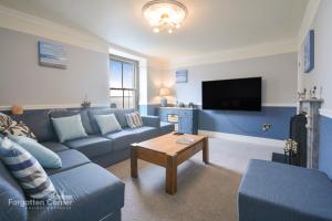 a living room with a blue couch and a tv at Kelvin House - Cawsand in Cawsand