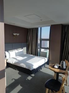 a bedroom with a bed and a table and a chair at J Hotel in Ulaanbaatar