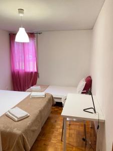Cette chambre comprend 2 lits, une table et une fenêtre. dans l'établissement Duplex Próximo do Aeroporto Lisboa, à Lisbonne