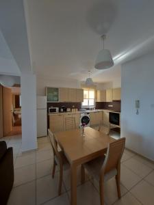 a kitchen and dining room with a wooden table and chairs at Pyla Palms Resort - 1 bedroom in Pyla