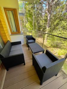 a porch with couches and chairs on a deck at Sunny Pobierowo Euronia Apartament in Pobierowo