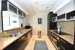 cocina con armarios marrones y fregadero en 2-BR Marina View Retreat at Marina Quays - DSY, en Dubái