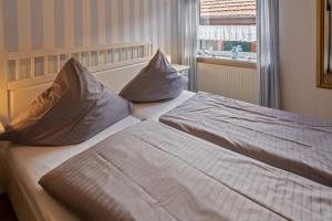 two beds in a hotel room with pillows on them at Strandkorb in Neßmersiel