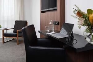 a room with a desk with a laptop and a chair at Rydges Latimer Christchurch in Christchurch