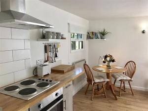 a kitchen with a stove and a table with chairs at Secret Chalet in Newton Poppleford