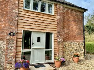 a brick house with a white door and flower pots at Bamford Barn in Ottery Saint Mary