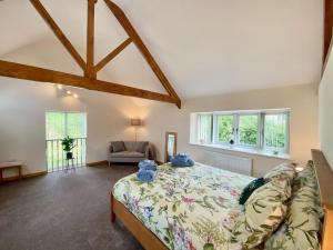 a bedroom with a bed and a couch and windows at Bamford Barn in Ottery Saint Mary