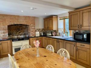 Una cocina con una mesa de madera con un jarrón de flores encima. en The Teddy House, en Ottery St Mary