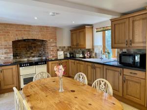 a kitchen with a wooden table with a vase of flowers on it at The Teddy House in Ottery Saint Mary