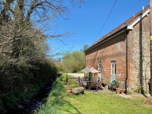 un antiguo edificio de ladrillo con una mesa y una sombrilla en The Teddy House, en Ottery St Mary