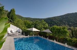 una piscina con sedie, ombrelloni e montagna di Stunning 4-Bed House in Benamahoma a Benamahoma
