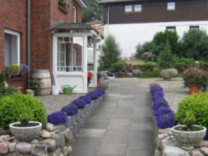 a garden with purple flowers in front of a house at Ferienhaus Tobie in Ahlefeld