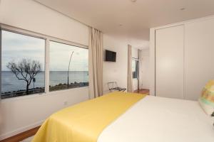 a bedroom with a yellow bed and a large window at Ocean Views by Azores Villas in Ponta Delgada