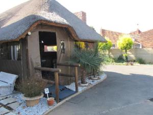 a small house with a thatched roof with plants at Mall Guesthouse in Vanderbijlpark