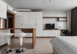 Cet appartement comprend une chambre avec un lit et une cuisine avec des placards blancs. dans l'établissement Апарт-отель YE'S Mitino, à Moscou