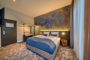 a bedroom with a bed and a painting on the wall at NYCE Hotel Bonn in Bonn