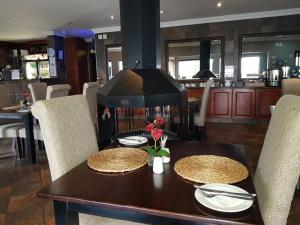 a dining room table with two plates and flowers on it at Magalies Mountain Lodge and Spa in Hartbeespoort